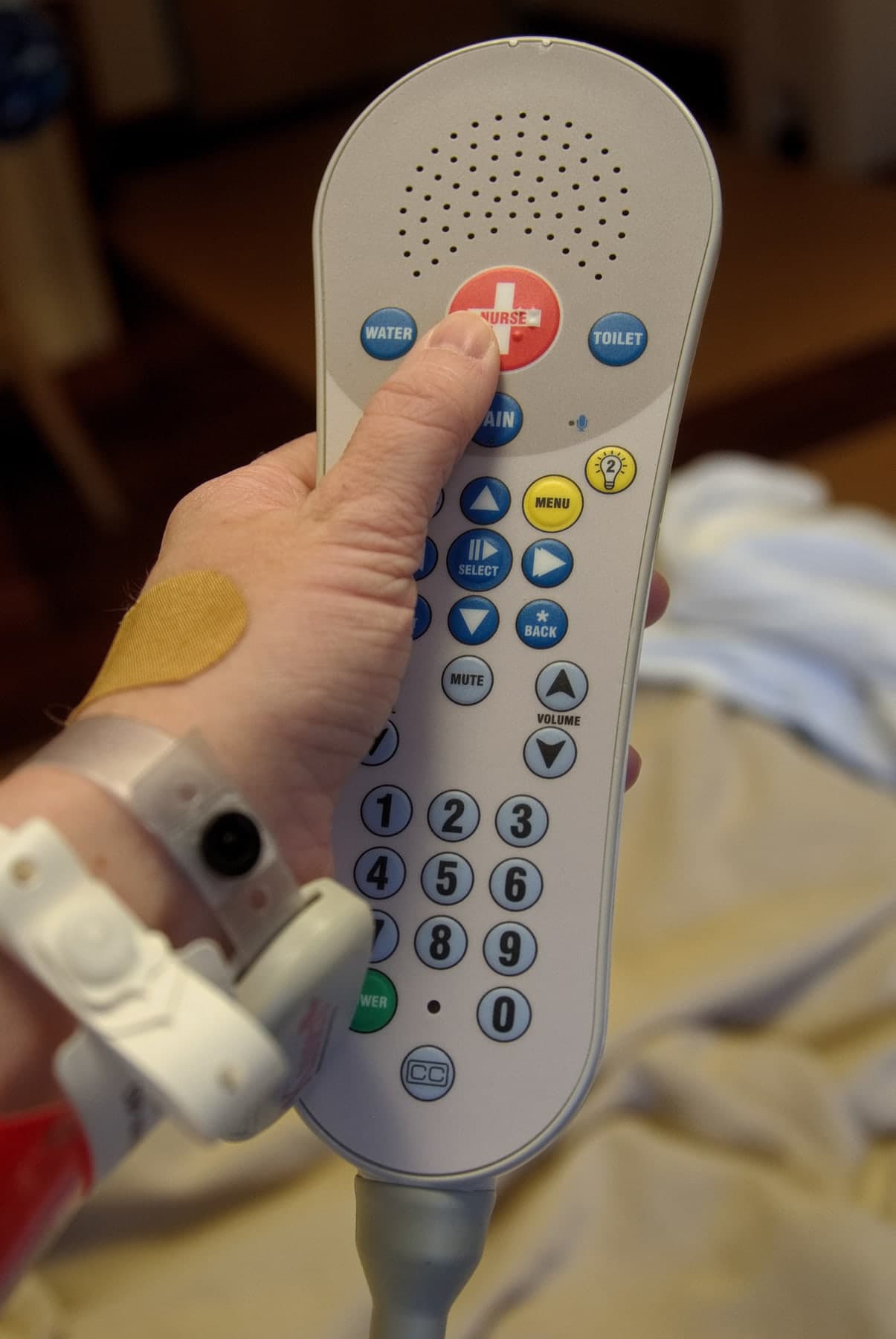Patient pressing a nurse call button on a pillow speaker